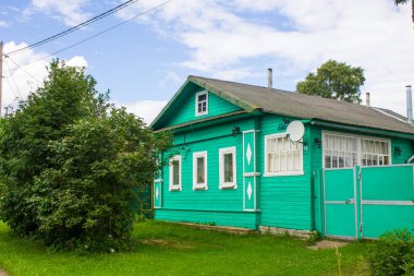 Eski ahşap kulübelerin ve yeşil ağaçların olduğu bir sokak.