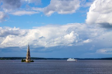 Su altında bir çan kulesi ve Rusya 'nın Kalyazin şehrindeki Volga nehrinde beyaz bir yolcu gemisi bulutlu bir yaz gününde ve bir fotokopi alanı