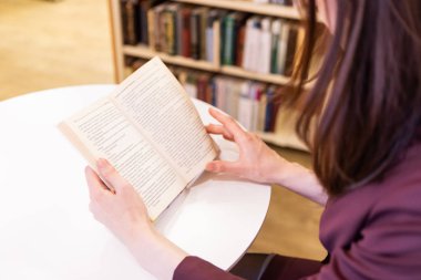 Bir kitap Holding genç kadınlar eller. Kütüphanede okuma, yakın çekim seçici odak, Işıksaçan gösterge