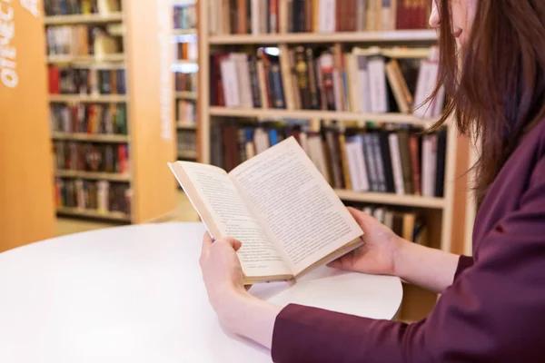 Bir kitap Holding genç kadınlar eller. Kütüphanede okuma, yakın çekim seçici odak, Işıksaçan gösterge