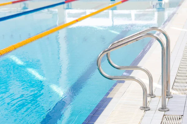 Metal Handrail, Grab bars Ladder For Swimmers In The Pool With Blue Water And Colored Dividers Of Swimming Track