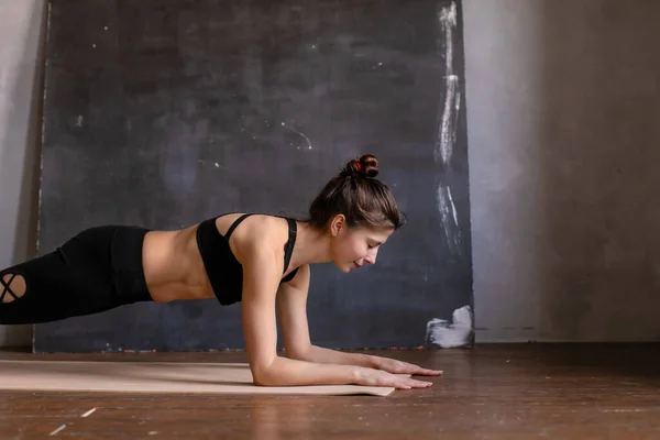 Yoga pozisyonunda duran genç bir kadın. Dirsekleriyle kalas yapan kız, yoga dersinde germe egzersizi yapan kız..
