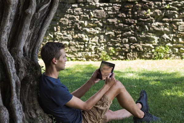 Man reading tablet and enjoy rest in a park under tree