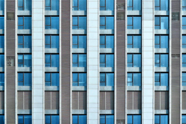 Front of a corporate building, many windows reflecting the sky.