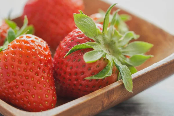 macro color picture of strawberries in a wooden bowl