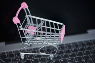 Çevrimiçi alışveriş için dizüstü bilgisayarda pembe minyatür alışveriş arabası