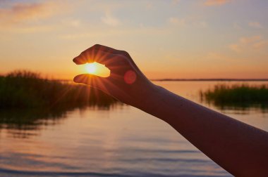 Gün batımının önünde, Almanya 'nın Bavyera kentindeki Chiemsee' de gün batımında güneşi alan çocuk el.