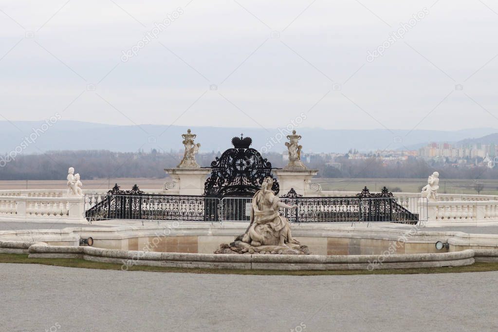 Royal garden in French style: statues, pond, wrought iron gates, gravel paths