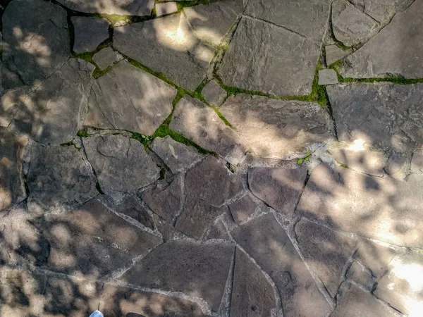 Stone floor, Stone Wall From A Large Granite Cobblestone Close-Up. Growing green moss between the seams