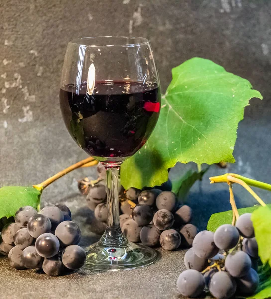 黒を基調としたワイングラスの中のブドウ 緑の葉を持つブドウの実 — ストック写真
