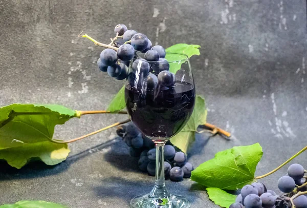 黒を基調としたワイングラスの中のブドウ 緑の葉を持つブドウの実 — ストック写真