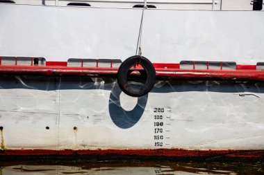 Beyaz bir teknede halatla bağlanmış bir arabanın lastiği.