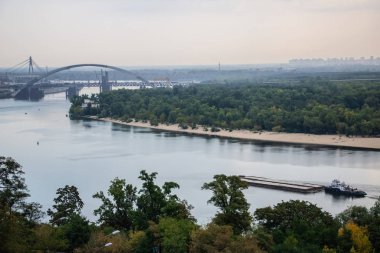 Avrupa 'nın merkezinde Kiev turu. Dinyeper manzarası, Trukhanov adası ve bir ayak köprüsü. Park çeşmesi ve gün batımı ufukta.
