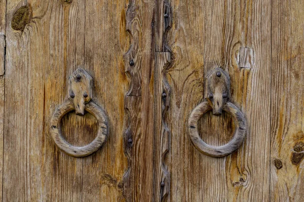 Old wooden door with round wooden handles. To knock on the door, close-up