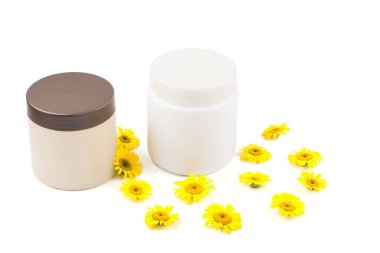 Kahverengi kapak ve beyaz kavanoz, krem, merhem, beyaz arka plan üzerinde küçük sarı papatyalar maskeyle mocap bej kavanozu. Ayrı tutma, yakın çekim, açık görünüm