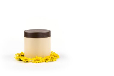 Kahverengi kapak, krem, merhem, maske ve beyaz bir arka plan üzerinde küçük sarı papatyalar mocap bej kavanozu. Ayrı tutma, yakın çekim, açık görünüm