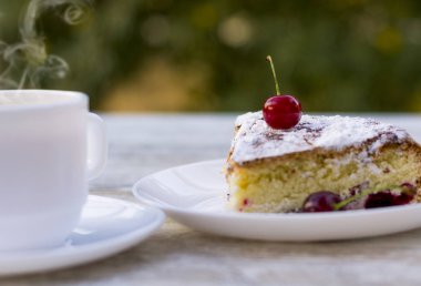 Kirazlı turta beyaz bir tabak ve beyaz fincan limon ile çay lezzetli bir parça. Yakın çekim. MoCap.