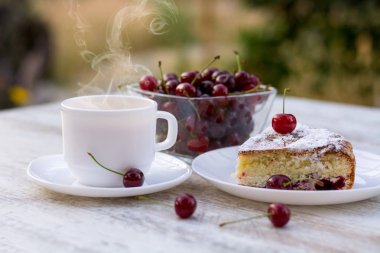 Kirazlı turta beyaz bir tabak ve beyaz fincan limon ile çay lezzetli bir parça. Yakın çekim. MoCap.