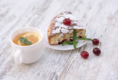 Kirazlı turta beyaz bir tabak ve beyaz fincan çay limon ve nane ile lezzetli bir parça. Yakın çekim. MoCap.