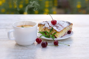 Beyaz bir tabak ve limon ve nane ile sıcak çay beyaz bir fincan kiraz pasta lezzetli bir parça. Close. Mocap, ne kadar çok şey var? Alanı, metin için alanı kopyalama.