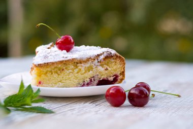 Beyaz tabak yakın tarihinde kirazlı turta nefis bir parça. Yaz yiyecek. Güzel kokulu nane Şubesi