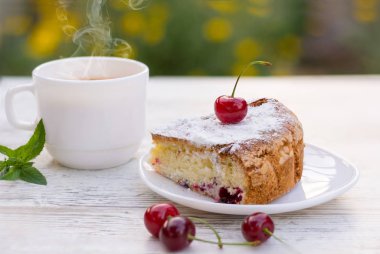 Kirazlı turta beyaz bir tabak ve beyaz fincan çay limon ve nane ile lezzetli bir parça. Yakın çekim. MoCap.