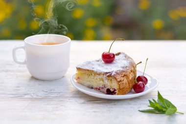 Kirazlı turta beyaz bir tabak ve beyaz fincan çay limon ve nane ile lezzetli bir parça. Yakın çekim. MoCap.