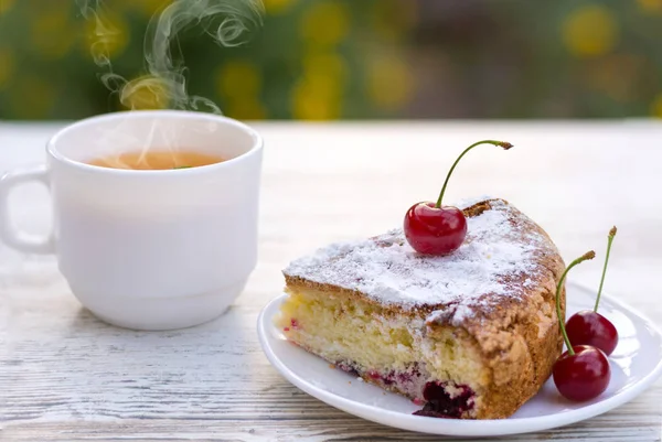 Beyaz bir tabak ve limon ile sıcak çay beyaz bir fincan kiraz pasta lezzetli bir parça. Close. Mocap, ne kadar çok şey var? Alanı, metin için alanı kopyalama