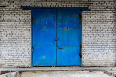 Iron gate, beyaz tuğla bina kilitlendiğinde ve mavi boya ile boyanmış. Ambar, depolama