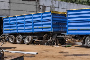 Bir mavi römork kamyon bir benzinlikte tamir ediliyor.