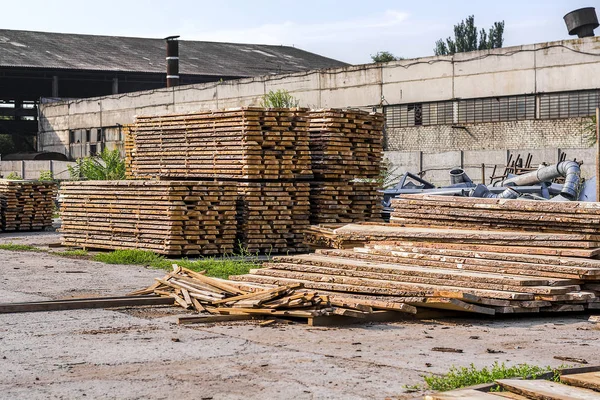 Stacks of wooden planks at a sawmill. Warehouse for sawing in the sawmill outdoors.