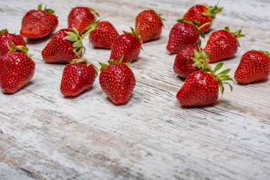 Dağınık taze Olgun kırmızı çilek çok hafif dokulu ahşap bir masa üzerinde yalan söylüyorsun. Boşaltmak.