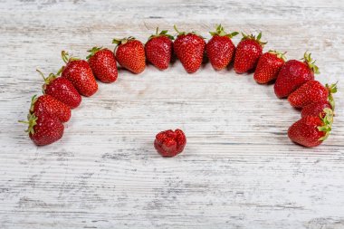 Taze Olgun kırmızı çilek bir ark hafif dokulu ahşap bir masa üzerinde yatıyor. Flatlay, boşaltmak