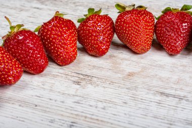 Taze Olgun kırmızı çilek bir ark hafif dokulu ahşap bir masa üzerinde yatıyor. Flatlay, boşaltmak
