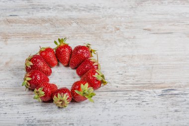 Taze Olgun kırmızı çilek bir ark hafif dokulu ahşap bir masa üzerinde yatıyor. Flatlay, boşaltmak