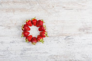 Taze Olgun kırmızı çilek bir ark hafif dokulu ahşap bir masa üzerinde yatıyor. Flatlay, boşaltmak