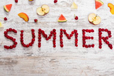 Inscription Summer of raspberry berries on a textured light wooden background. Slices of fruit, apple, peach, melon, watermelon. Flat top view, place for text. Flat Lay, Copy Space.