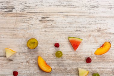 Meyve, şeftali, kavun, karpuz, üzüm, Erik, ahududu, dilim yalan dokulu bir ışık ahşap arka plan üzerinde. Düz üst görünümü, metin için yer. Yat, alanı Kopyala. Yaz arka plan.
