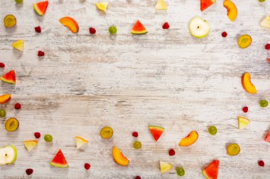 Adet meyve, elma, şeftali, kavun, karpuz, üzüm, Erik, ahududu, dokulu bir ışık ahşap arka plan üzerinde yalan. Düz üst görünümü, metin için yer. Yat, alanı Kopyala. Yaz arka plan.