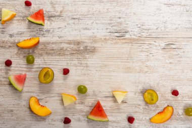 Meyve, şeftali, kavun, karpuz, üzüm, Erik, ahududu, dilim yalan dokulu bir ışık ahşap arka plan üzerinde. Düz üst görünümü, metin için yer. Yat, alanı Kopyala. Yaz arka plan.