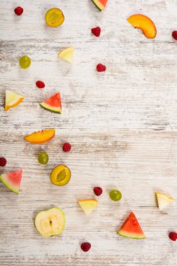 Adet meyve, elma, şeftali, kavun, karpuz, üzüm, Erik, ahududu, dokulu bir ışık ahşap arka plan üzerinde yalan. Düz üst görünümü, metin için yer. Yat, alanı Kopyala. Yaz arka plan.