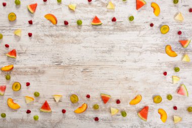 Adet meyve, elma, şeftali, kavun, karpuz, üzüm, Erik, ahududu, dokulu bir ışık ahşap arka plan üzerinde yalan. Düz üst görünümü, metin için yer. Yat, alanı Kopyala. Yaz arka plan.