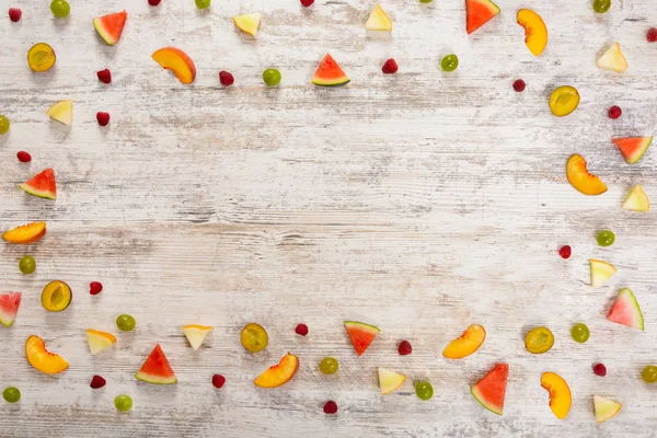 Adet meyve, elma, şeftali, kavun, karpuz, üzüm, Erik, ahududu, dokulu bir ışık ahşap arka plan üzerinde yalan. Düz üst görünümü, metin için yer. Yat, alanı Kopyala. Yaz arka plan.