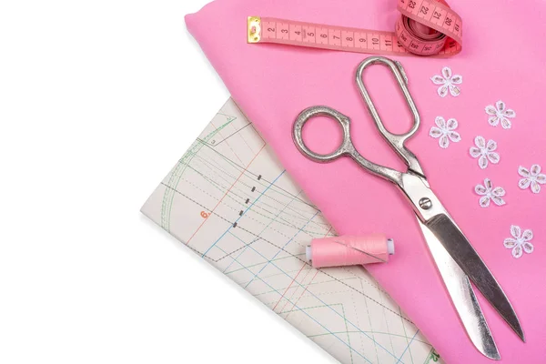 Tailoring. Sewing accessories and accessories for sewing and needlework. Scissors, centimeter, pattern, spool of thread and fabric of pink color on a white background. Isolate, Flat Lay, Copy Space