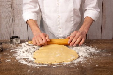 Kurabiye, turta, kek, pizza için hamur hazırlığı. Eller mutfak closeup, ahşap bir masa üzerinde bir oklava ile hamur dışarı rulo. Alanı, metin için alanı kopyalama