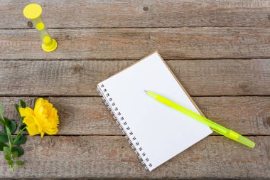 Zaman. Kum saati, kayıtlar için boş bir defter, ahşap tahtaların arka planında bir kalem ve bir gül. Vintage, Flat Lay, Copy alanı, Mock up