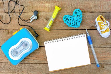 Zaman. Kum saati, ahşap tahtaları arka planda kayıtlar ve ses kaseti çalar için boş bir defter. Vintage, düz Lay, kopya alanı, mock up