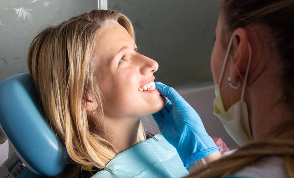 Стоматология. Пациентка - девочка-подросток, вид сбоку. Врач проверяет укус челюсти крупным планом.
.