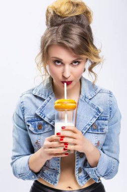 Gıda Kavramlar. Fincan süt ve çörek çörek ile eğleniyor genç Beyaz sarışın kız. Straw.Vertical resim kompozisyon ile süt içerken