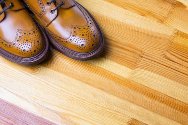 Ayakkabı fikirler ve kavramlar. İpuçları erkeğin Brooge çizme Tan renkli closeup. Ahşap sarımsı Background.Horizontal vuruşta ayakta